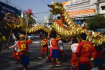Thailand, Bangkok, young men in costume carry Dragon in parade celebrating local Chinese temple on New Road, first paved road in the city.
