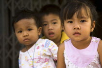 Thailand, Bangkok, Young children in late afternoon sun in front of shophouse entrance.