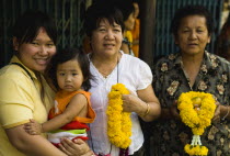 Thailand, Bangkok, Four female generations of family with floral garlands to celebrate the annual blessing of local temple.