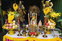 Thailand, Bangkok, Offerings on table with Guanyin Goddess of Mercy statue in centre celebrating local temple.