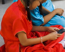 Thailand, Bangkok, Thai girls using mobile telephone in costume of dance troupe.