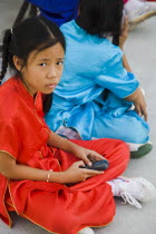 Thailand, Bangkok, Thai girls using mobile telephone in costume of dance troupe.