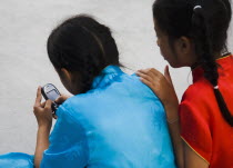 Thailand, Bangkok, Thai girls using mobile telephone wearing costume of dance troupe.