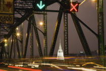 Thailand, Bangkok, Traffic flow control in evening rush hour on Saphan Phut Memorial Bridge, illuminated Stemple mstup in the background.