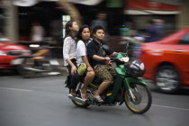 Thailand, Bangkok, Young Thai women on motorcycle without helmets, helmet in shopping basket blurred motion.