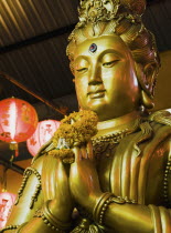 Thailand, Bangkok, Gold Guanyin Goddess of Mercy statue with red lanterns for Chinese New Year.