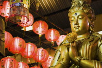 Thailand, Bangkok, Gold Guanyin Goddess of Mercy statue with red lanterns for Chinese New Year.