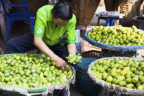 Thailand, Bangkok, stall holder displaying limes in Chinatown market.