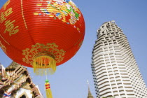 Thailand, Bangkok, Wat Yannawa temple roof and unfinished apartment block from 1990s Asian financial crash with red lanterns at Chinese New Year.