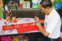 Thailand, Bangkok, Calligrapher painting Gold characters on red paper, auspicious colours for Chinese New Year.