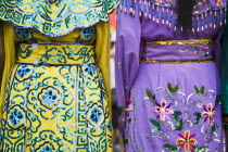 Thailand, Bangkok, Embroidered womens dresses viewed from behind.