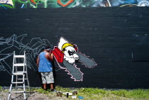 USA, Florida, Orlando, Graffiti artist painting wall.