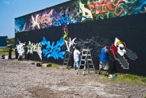 USA, Florida, Orlando, Graffiti artists painting wall.