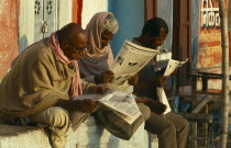 India, Uttar Pradesh, Varanasi, Men reading newspapers in the street.