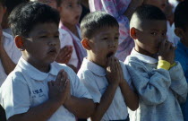 Thailand, Chiang Mai, Buddhist Schoolchildren with hands held in prayer, one child yawning.