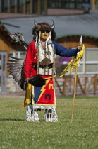 Canada, Alberta, Waterton Lakes National Park, Blackfoot dancer in a buffalo headdress and sunglasses wearing a porcupine quill breastplate and holding a spear and feather fan at the Blackfoot Arts &...