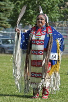 Canada, Alberta, Waterton Lakes National Park, Blackfoot dancer in blue cape trimmed withotter fur and porcupine quill apron holding a feather fan in the Women's Traditional Dance at the Blackfoot Art...