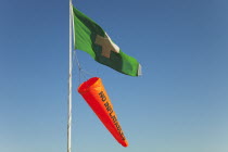 England, West Sussex, West Wittering Beach, Beach safety flags. White Cross on Green Flag signalling First Aid Point. Orange No Inflatables windsock.