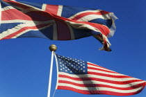 England, West Sussex, West Wittering Beach, British and United States of America flags flying against a blue sky.