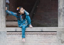 Nepal, Kathmandu, smiling young girl in traditional blue coloured dress and flowers in her hair.