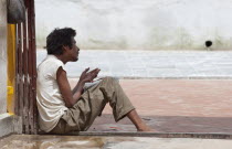 Nepal, Kthamandu, Sick man begs for alms near Swayambhunath Stupa.