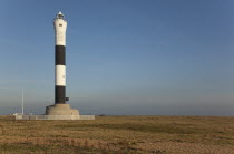 England, Kent, Romney Marsh, Dungeness, Black and white painted lighthouse on the shingle beach.