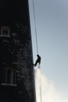 England, Kent, Romney Marsh, Dungeness, Man cleaning Lighthouse tower with pressure washer whilst abseiling.