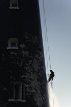 England, Kent, Romney Marsh, Dungeness, Man cleaning Lighthouse tower with pressure washer whilst abseiling.