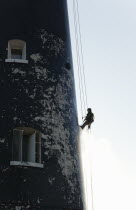 England, Kent, Romney Marsh, Dungeness, Man cleaning Lighthouse tower with pressure washer whilst abseiling.