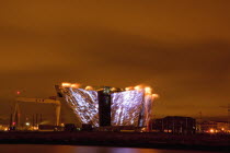 Ireland, North, Belfast, Titanic Quarter, Visitor centre designed by Civic Arts & Eric R Kuhne, illuminated during opening fireworks and projection display.