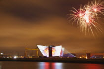 Ireland, North, Belfast, Titanic Quarter, Visitor centre designed by Civic Arts & Eric R Kuhne, illuminated during opening fireworks and projection display.