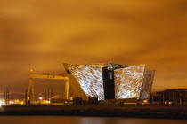 Ireland, North, Belfast, Titanic Quarter, Visitor centre designed by Civic Arts & Eric R Kuhne, illuminated at night.