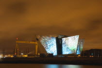 Ireland, North, Belfast, Titanic Quarter, Visitor centre designed by Civic Arts & Eric R Kuhne, illuminated at night.