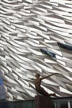 Ireland, North, Belfast, Titanic Quarter, Visitor centre designed by Civic Arts & Eric R Kuhne, with statue of diving woman in foreground.