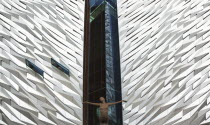 Ireland, North, Belfast, Titanic Quarter, Visitor centre designed by Civic Arts & Eric R Kuhne, with statue of diving woman in foreground.