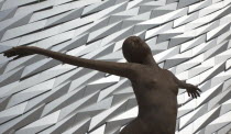 Ireland, North, Belfast, Titanic Quarter, Visitor centre designed by Civic Arts & Eric R Kuhne, with statue of diving woman in foreground.