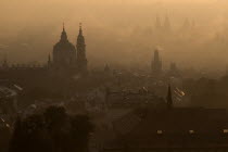 Czech Republic, Bohemia, Prague, Post dawn fog over the city with St Nicholas Cathedral in foreground.