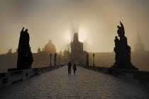 Czech Republic, Bohemia, Prague,  Strolling in the post dawn rays of sun and mist on Charles Bridge.