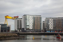 Ireland, North, Belfast, Titanic Quarter, Modern apartment blocks on the site of the Harland & Wolff shipyard with sightseeing cruise boat.