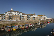 England, East Sussex, Brighton, view over fishing boats moored in the Marina with apartment buildings behind.