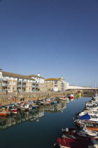 England, East Sussex, Brighton, view over boats moored in the Marina with apartment buildings behind.