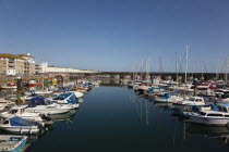 England, East Sussex, Brighton, view over boats moored in the Marina with apartment buildings behind.