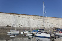 England, East Sussex, Brighton, Boats moored in the Marina with chalk cliffs behind.