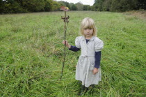 Kids, Outdoor, 5 year old Eva with stick & leaf flag in a field of grass.