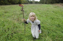 Kids, Outdoor, 5 year old Eva with stick & leaf flag in a field of grass.