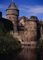 France, Bretagne, Ille-et-Vilaine, Fougeres. defensive walls and towers of the chateau dating from 11th to15th centuries rising from moat with blue sky beyond.