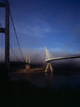 France, Bretagne, Finistere, Ile de Crozon. view of both old and new pont de terenez suspension bridges from north bank of the river aulne in early morning fog.