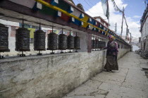 Nepal, Upper Mustang, Kagbeni, woman prays using prayer wheels.