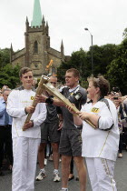 England, Kent, Tunbridge Wells, Olympic Torch relay, runners handing over torch by exchanging the flame.