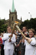 England, Kent, Tunbridge Wells, Olympic Torch relay, runners handing over torch by exchanging the flame.